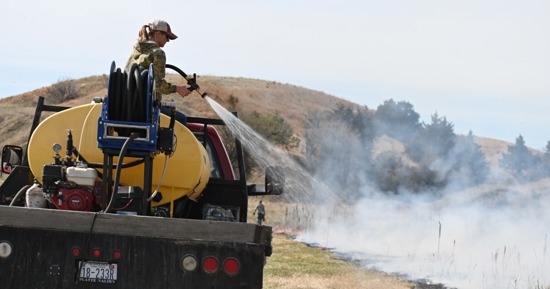 Ashley Larsen – Wet line – CAPTION: Ashley Larsen, burn volunteer, putting down a wet line around the perimeter of the fire.